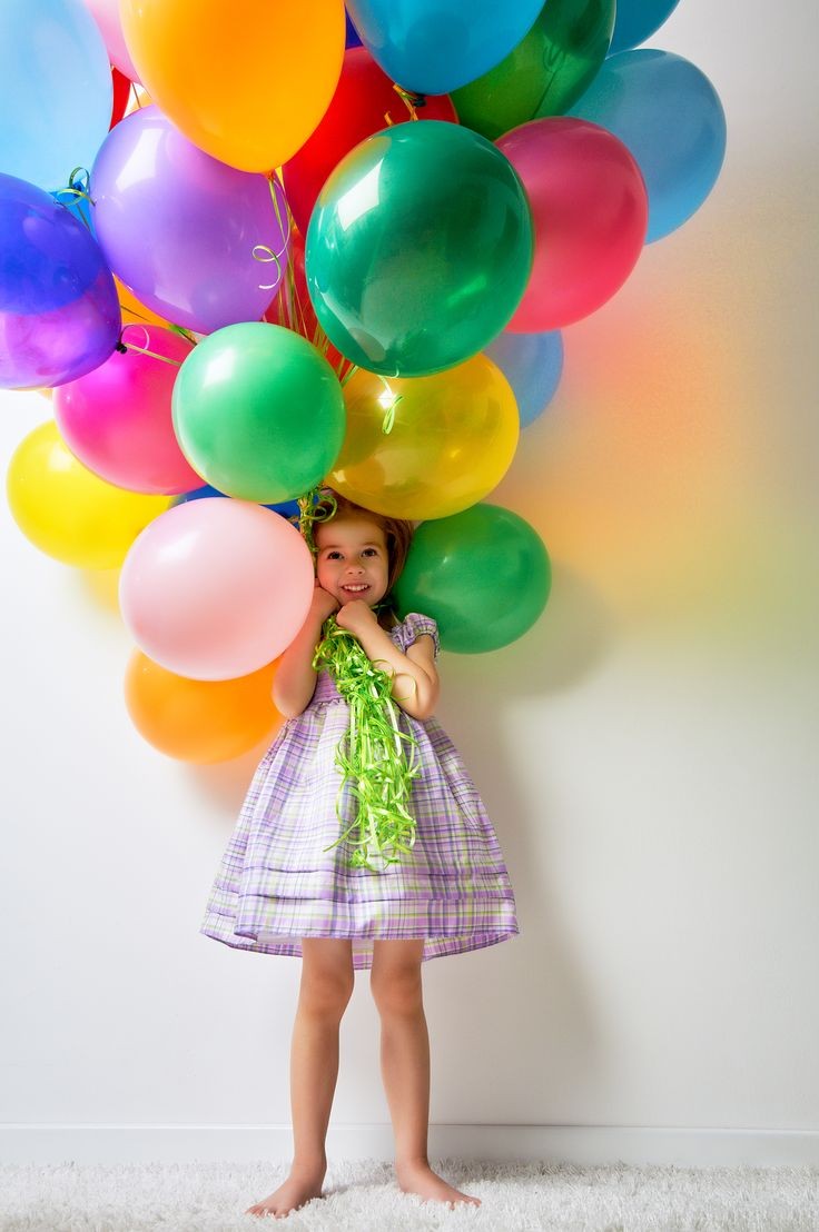 Küçük bir kızın elinde metalik uçan balon demeti