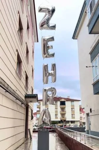 Sokakta yükselen gümüş harfli isim zinciri Apartmanlar arasındaki ıslak bir sokakta yükselen gümüş harf balonu zinciri